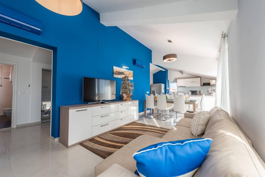 Vardagsrum med blå vägg och öppet kök