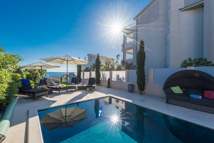 Soligt poolområde med havsutsikt