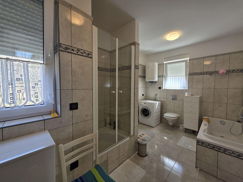 Stort badrum med dusch, badkar och tvättmaskin