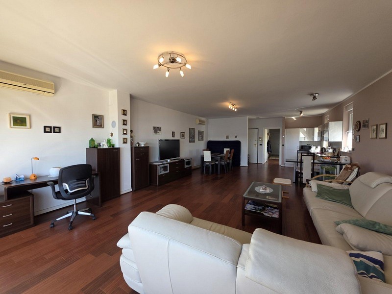 Ljust vardagsrum med parkettgolv, skinnsoffa och havsutsikt