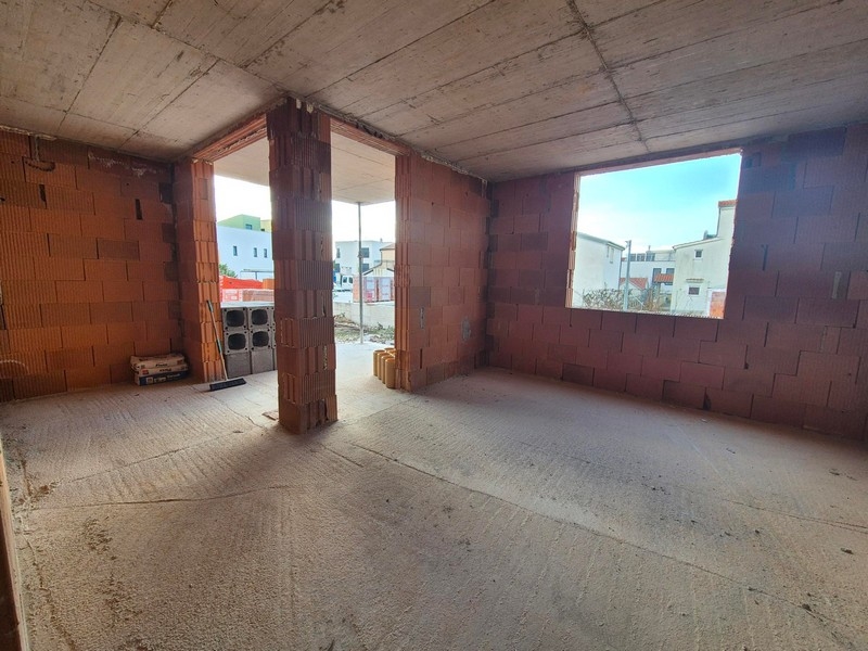 Skal av en lägenhet med synliga tegelväggar och ett stort fönster