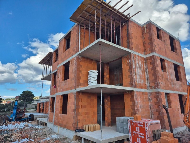 Nybyggnation av ett trevånings bostadshus med öppna balkonger och byggarbetsplatsmaterial