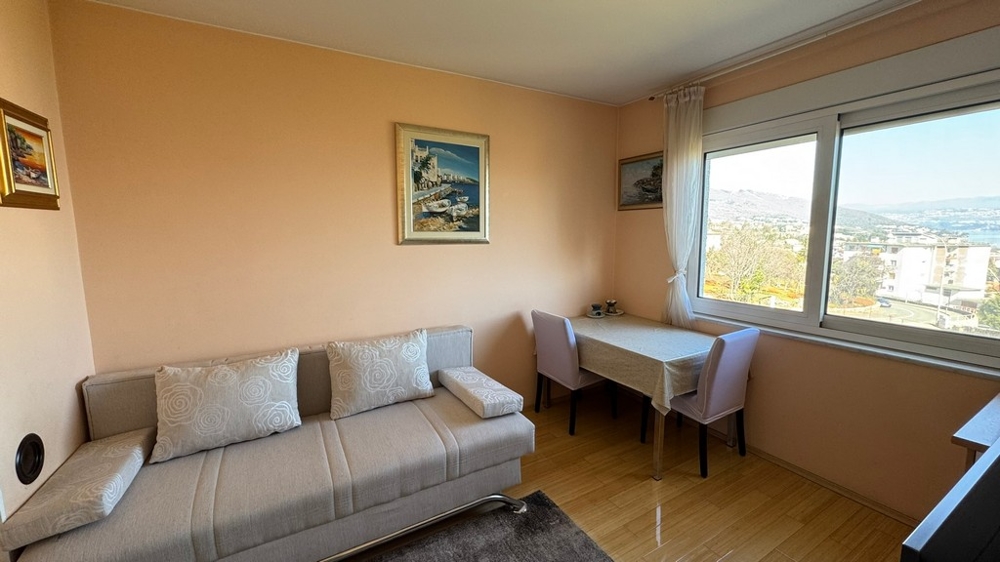 Vardagsrum med soffa, bord och stort fönster med havsutsikt