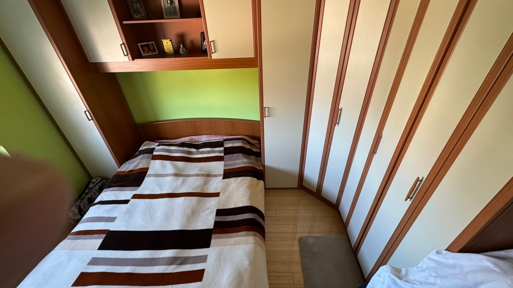 Sovrum med garderob och förvaringsfack ovanför sängen