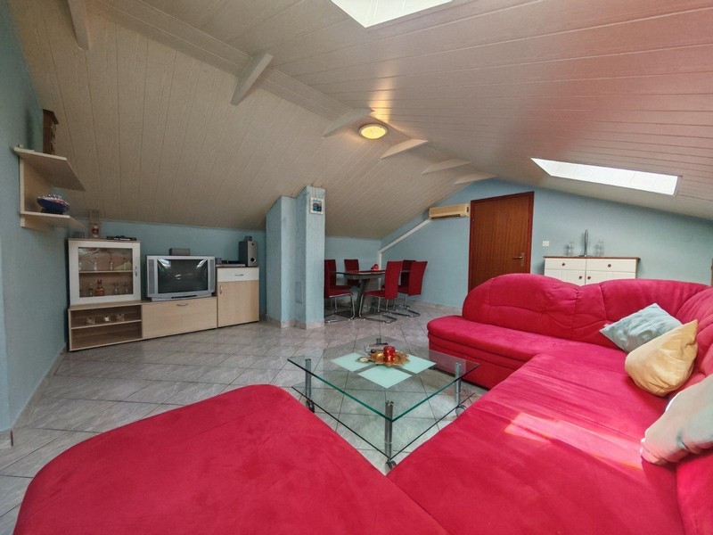 Vardagsrum med röd soffa under snedtak