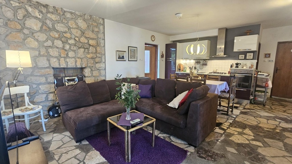 Vardagsrum med naturstensvägg och kök