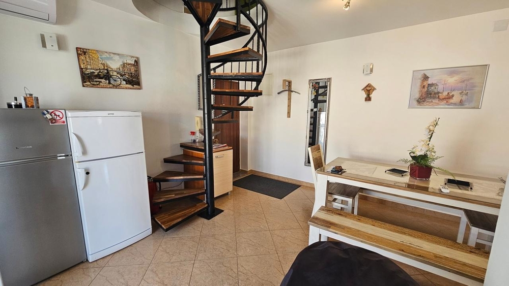 Vardagsrum med spiraltrappa och kylskåp