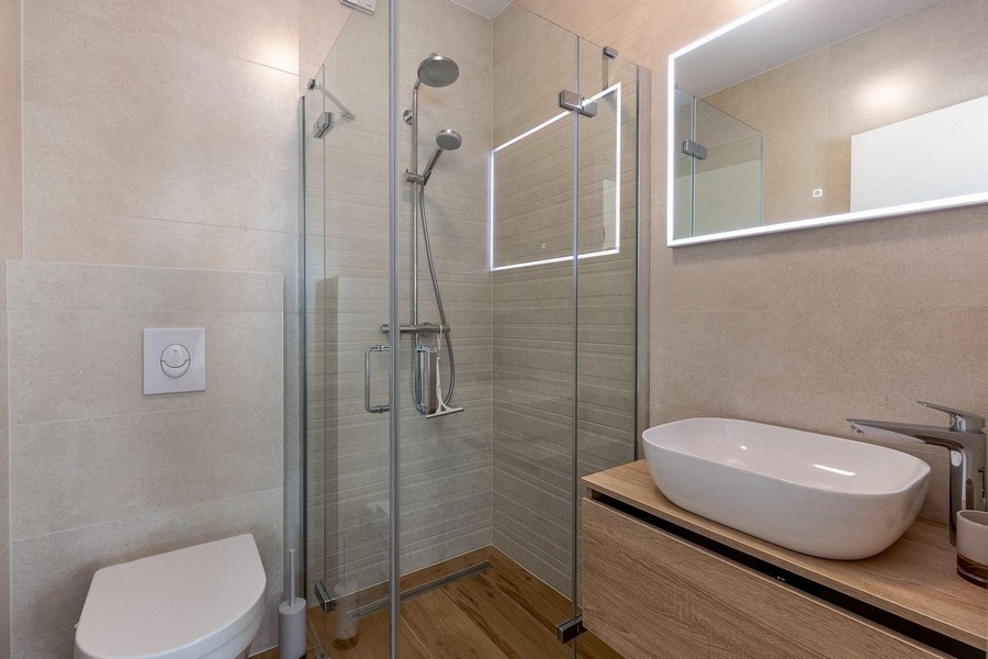 Badrum med glasdusch och trädetaljer