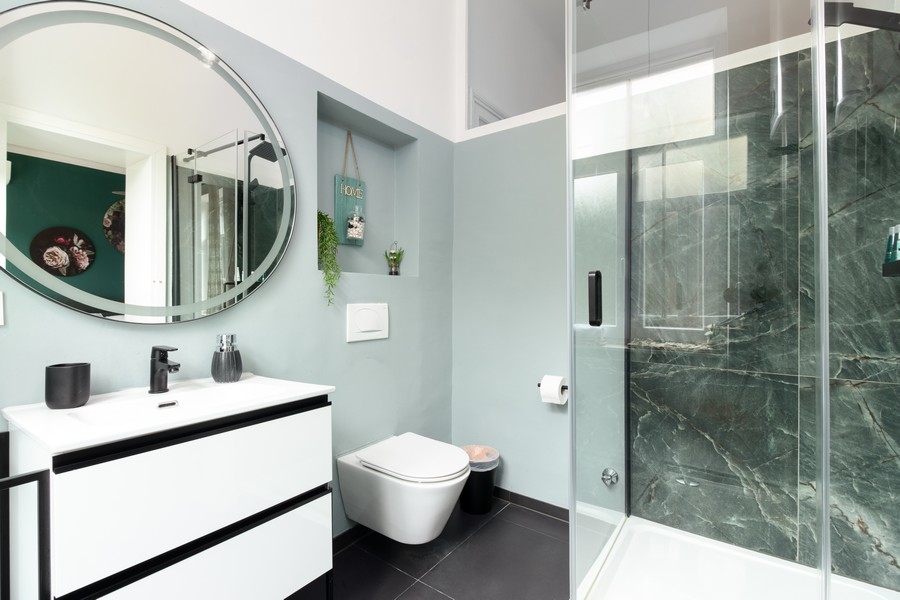 Badrum med rund spegel och glasdusch