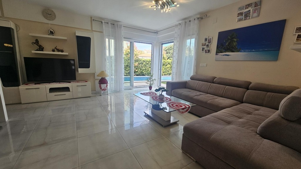 Ljust vardagsrum med hörnsoffa och TV