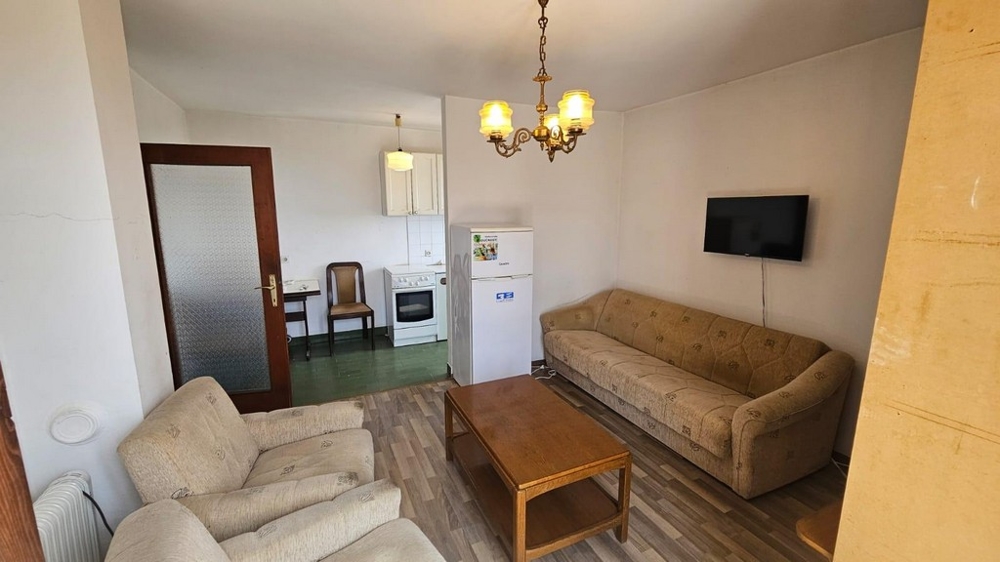 Vardagsrum med soffa och utsikt över köket