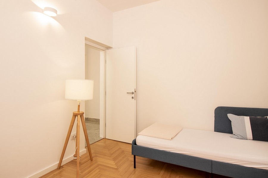 Andra sovrummet med golvlampa och trägolv