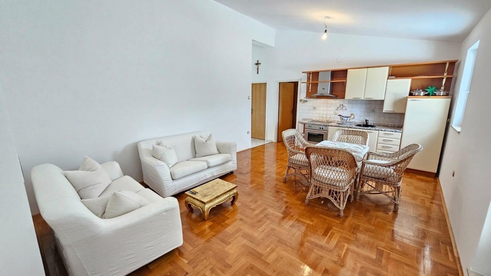 Vardagsrum med soffa, rottingstolar och kök