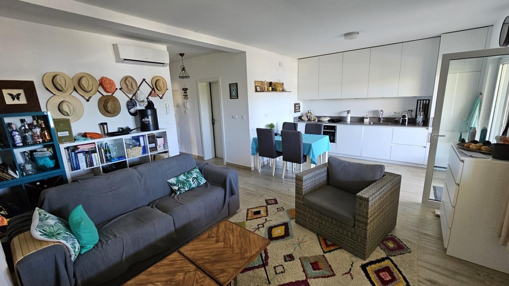 Vardagsrum med soffa, fåtölj och öppet kök