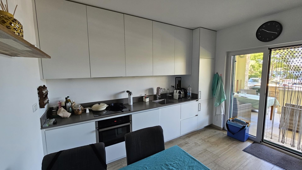 Modernt vitt kök med matplats och utgång till terrass