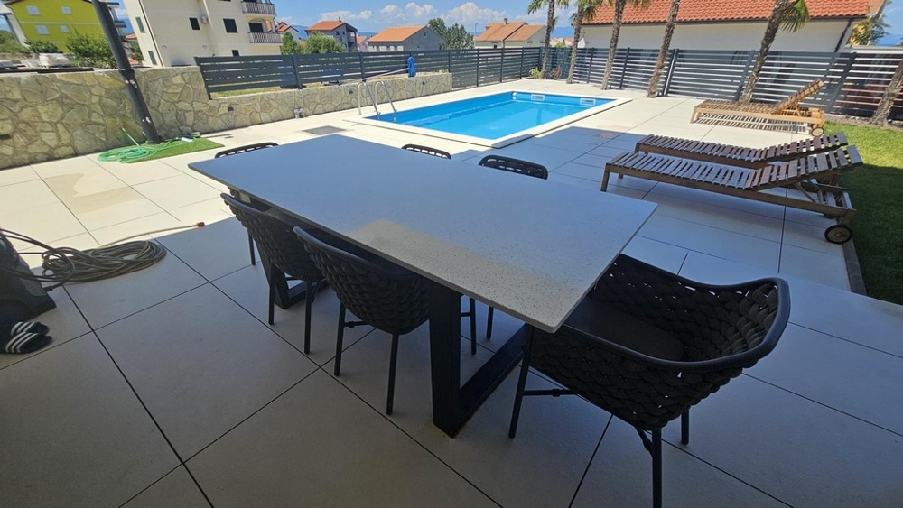 Terrass med matbord, poolutsikt och solstolar