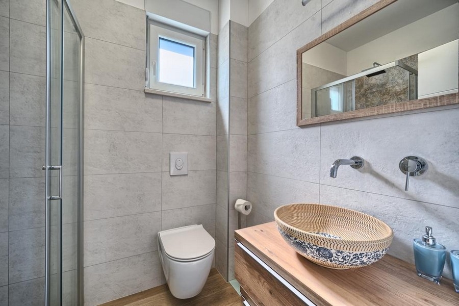 Modernt badrum med dusch, toalett och fönster