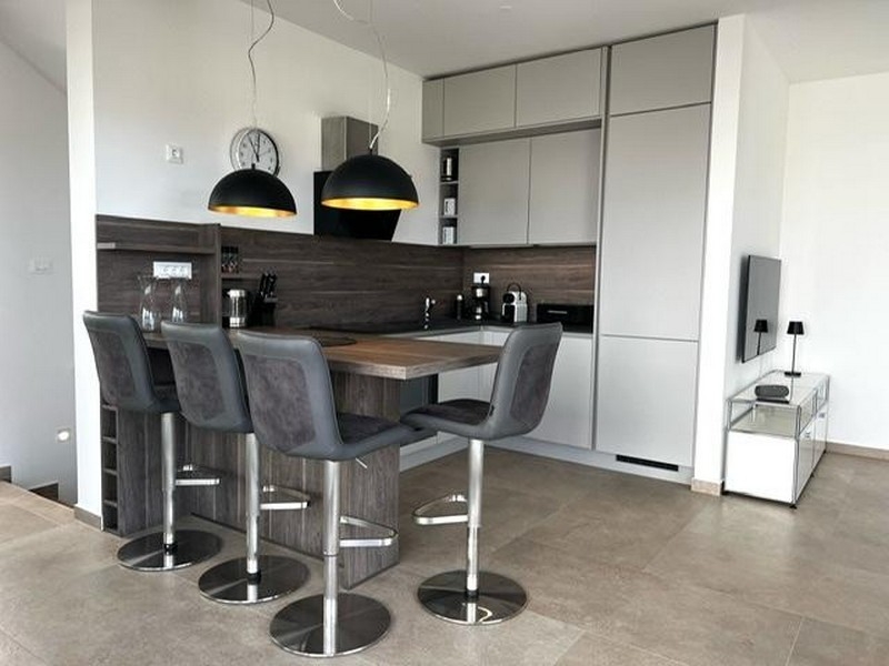 Modernt utrustat kök med bardisk och pallar