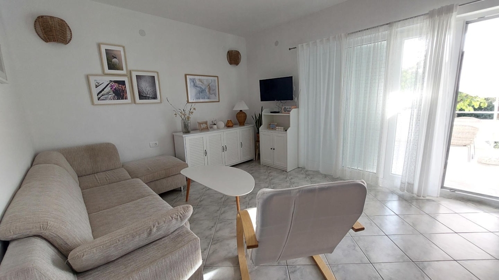 Ljust vardagsrum med soffa, fåtölj och utgång till altan