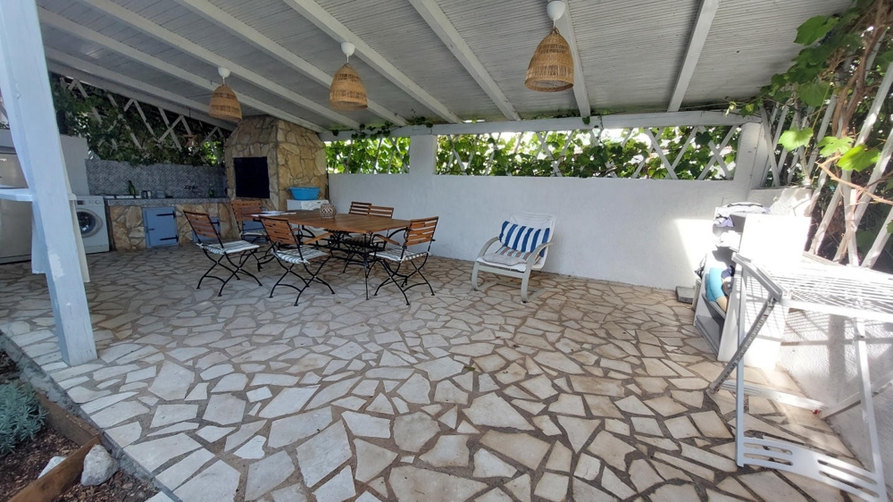 Sommarkök under tak med matbord och grillplats