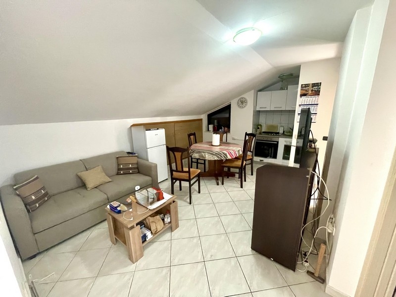 Vardagsrum med soffa, matbord och integrerat kök