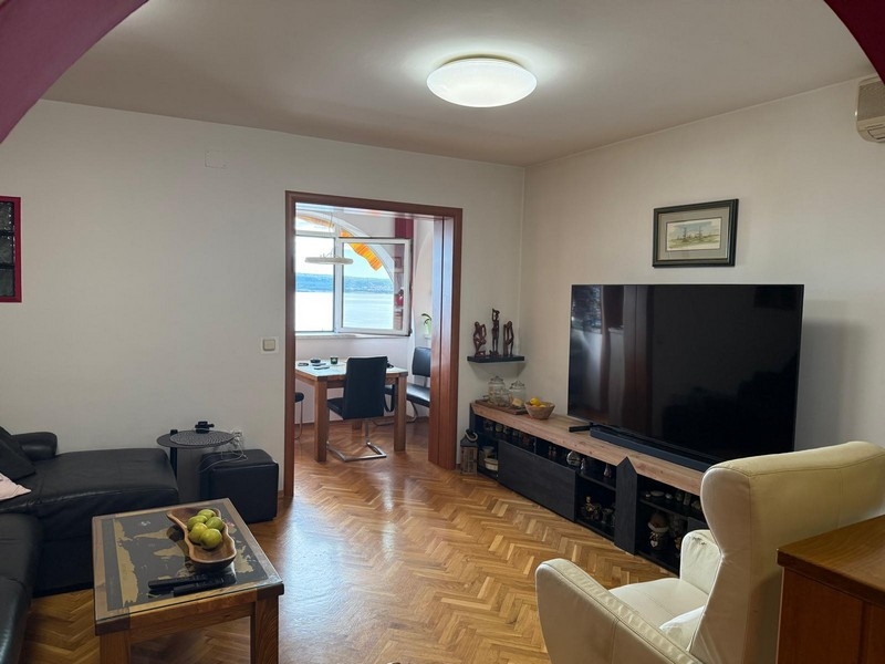 Vardagsrum med TV och havsutsikt i bakgrunden