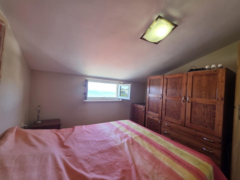 Sovrum med dubbelsäng och fönster med havsutsikt.