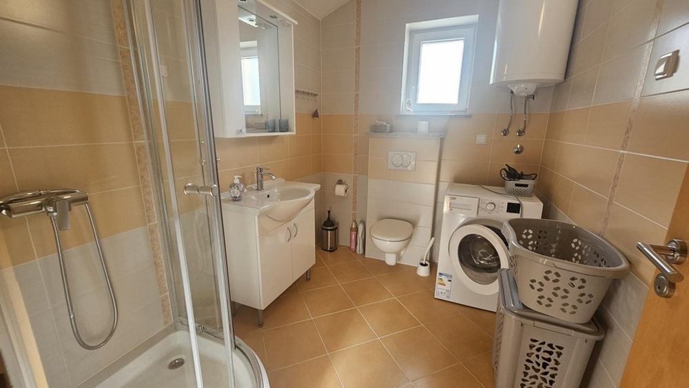 Badrum med dusch, tvättmaskin och fönster