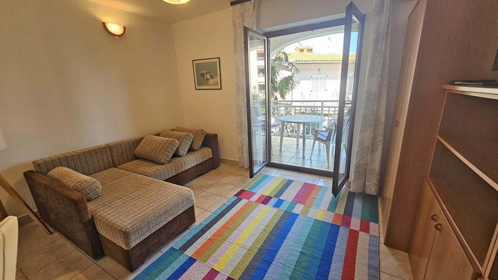 Vardagsrum med soffa, heltäckningsmatta och utgång till balkong