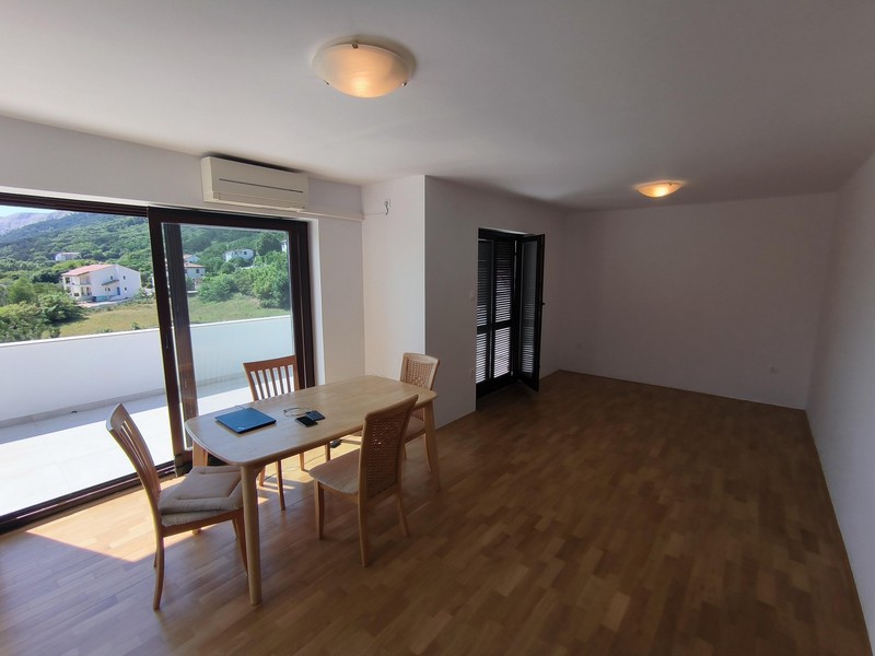 Ljust vardagsrum med parkettgolv och utgång till altan