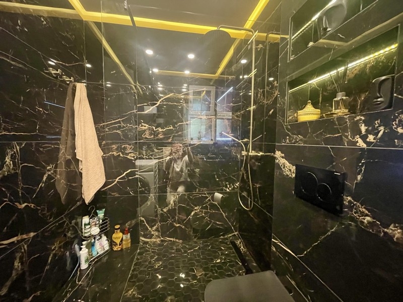 Badrum med stor duschkabin och design i svart marmor