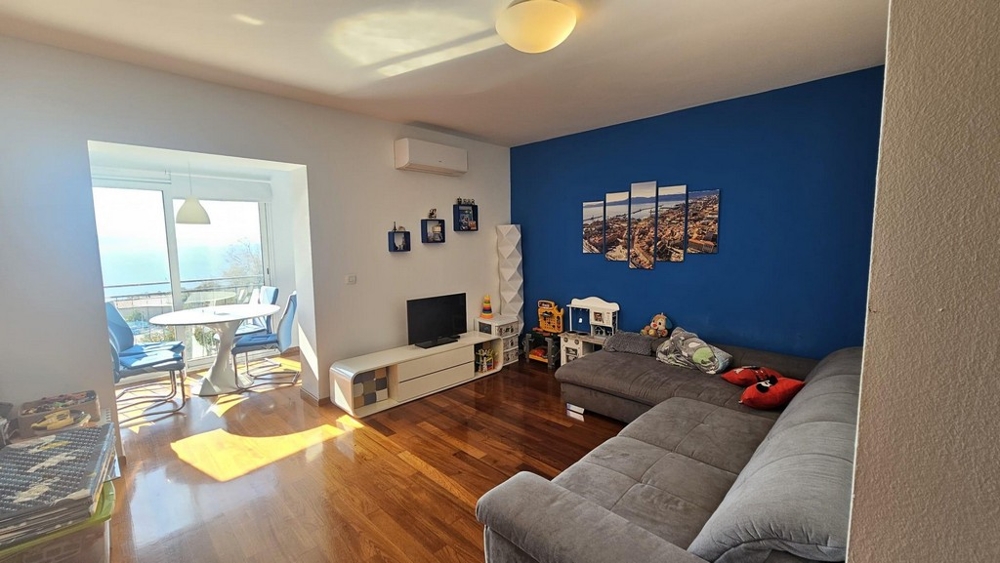 Vardagsrum med grå hörnsoffa och blå väggdesign