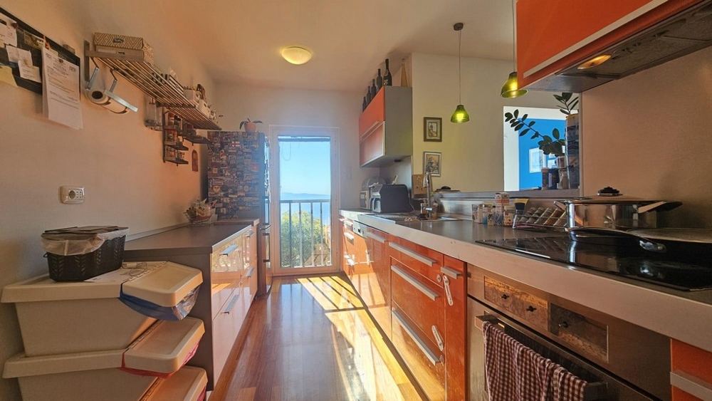 Kök med orange fronter och havsutsikt genom balkongdörr