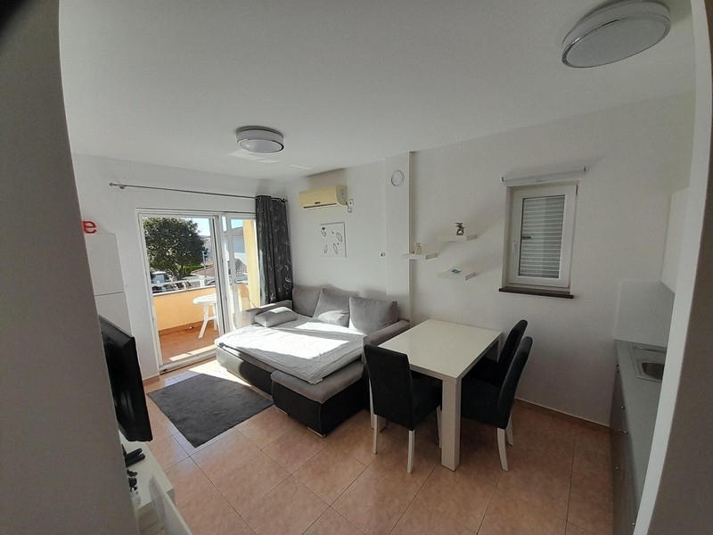 Vardagsrum med soffa, matbord och tillgång till balkong med havsutsikt