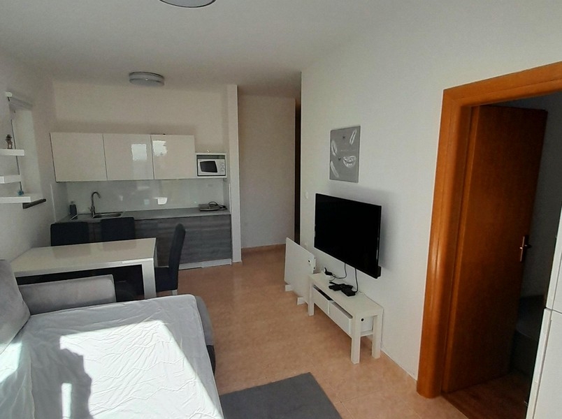 Vardagsrum med tv, matbord och tillgång till sovrummet