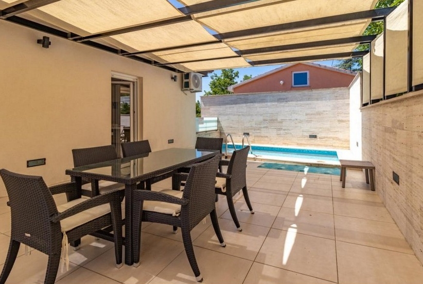 Täckt terrass med matplats och utsikt över poolen