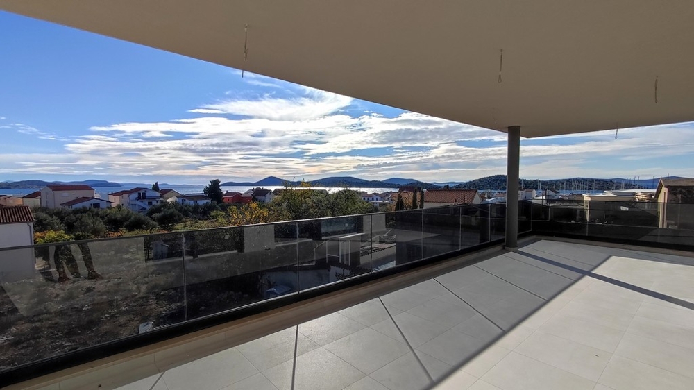 Stor täckt terrass med utsikt över hustaken och havet