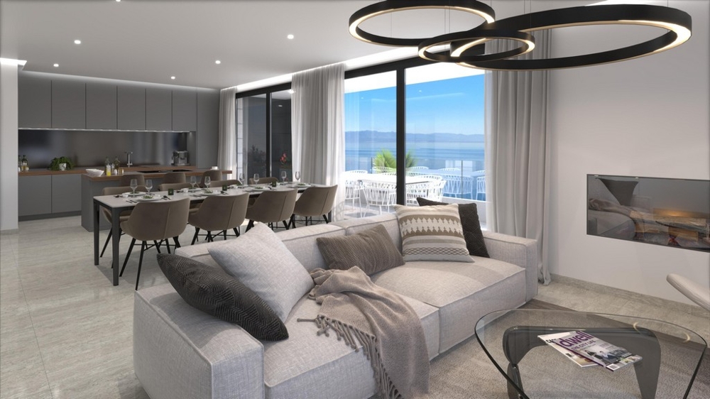 Öppen planlösning med vardagsrum och matplats med kök och havsutsikt