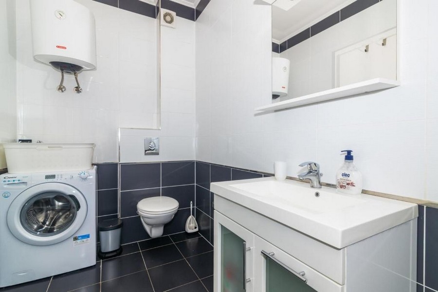 Badrum med handfat, wc och tvättmaskin