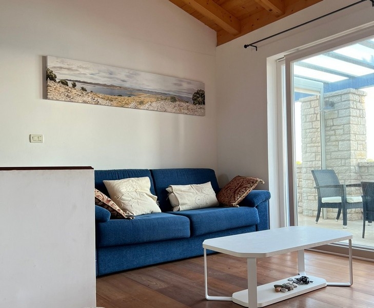 Vardagsrum med soffa och tillgång till altan under tak