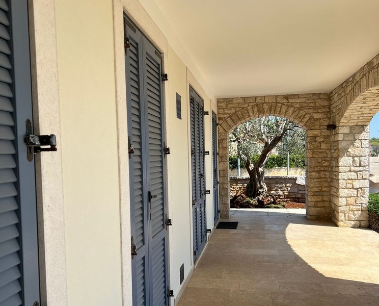 Täckt entréområde med naturstensvalv och fönsterluckor