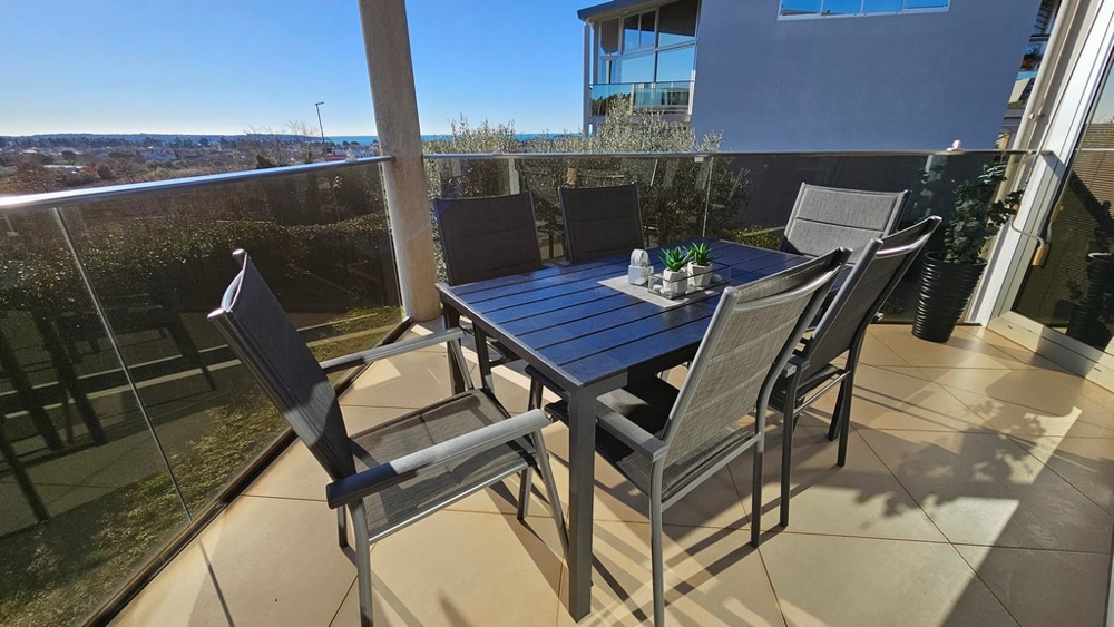 Täckt terrass med havsutsikt och sittgrupp