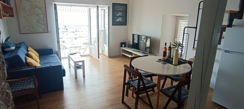 Vardagsrum med soffa, matbord och tillgång till balkong med havsutsikt