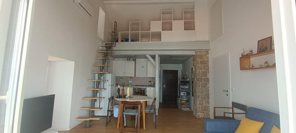 Vardagsrum med galleri, trappa och integrerat kök