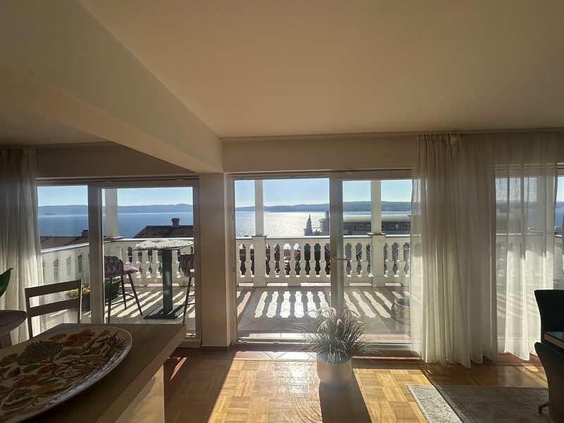 Vardagsrum med stort fönsterfront och tillgång till balkong med havsutsikt