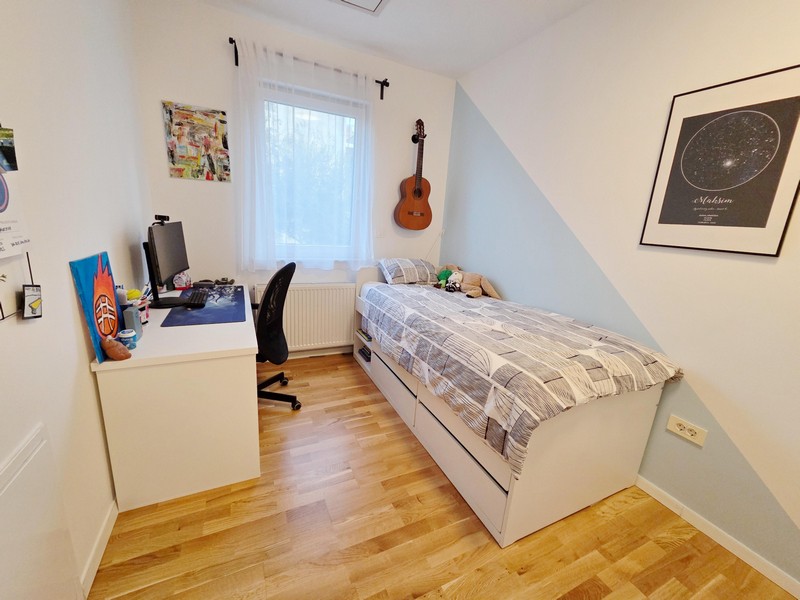 Ungdomsrum med skrivbord, säng och gitarr på väggen