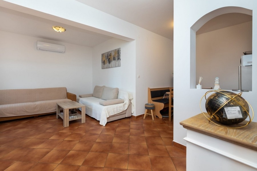 Lägenhetens vardagsrum med sittplatser och genomgång till köket