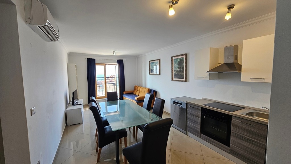 Ljust vardagsrum med öppet kök, matplats och havsutsikt