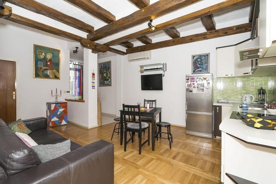 Vardagsrum med kök och matplats och takbjälkar i trä