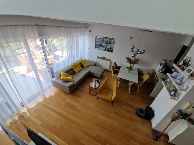 Ljust vardagsrum med galleri och stora fönsterpartier